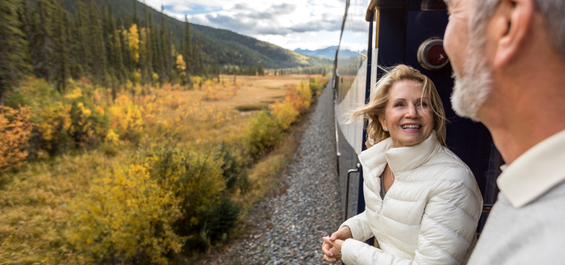 couple smiling on the GoldLeaf service platform on rocky mountaineer