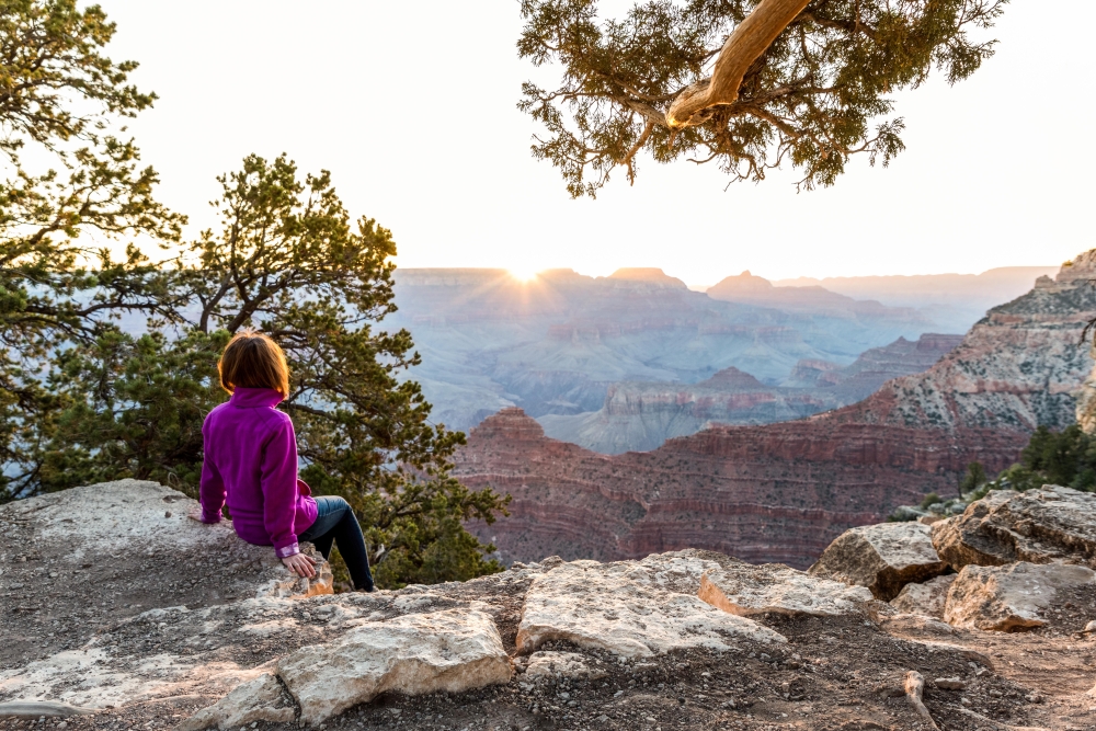 Tourist Is Seating On The Edge of Cliff and Watching of Sunrise at Grand Canyon from Mather Point